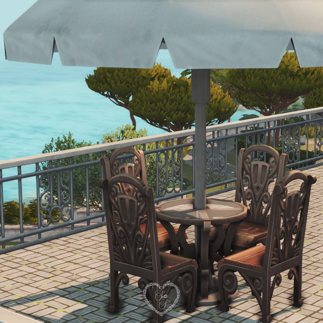 Patio set with ornate wooden chairs and an umbrella overlooking a coastal view in Tartosa.
