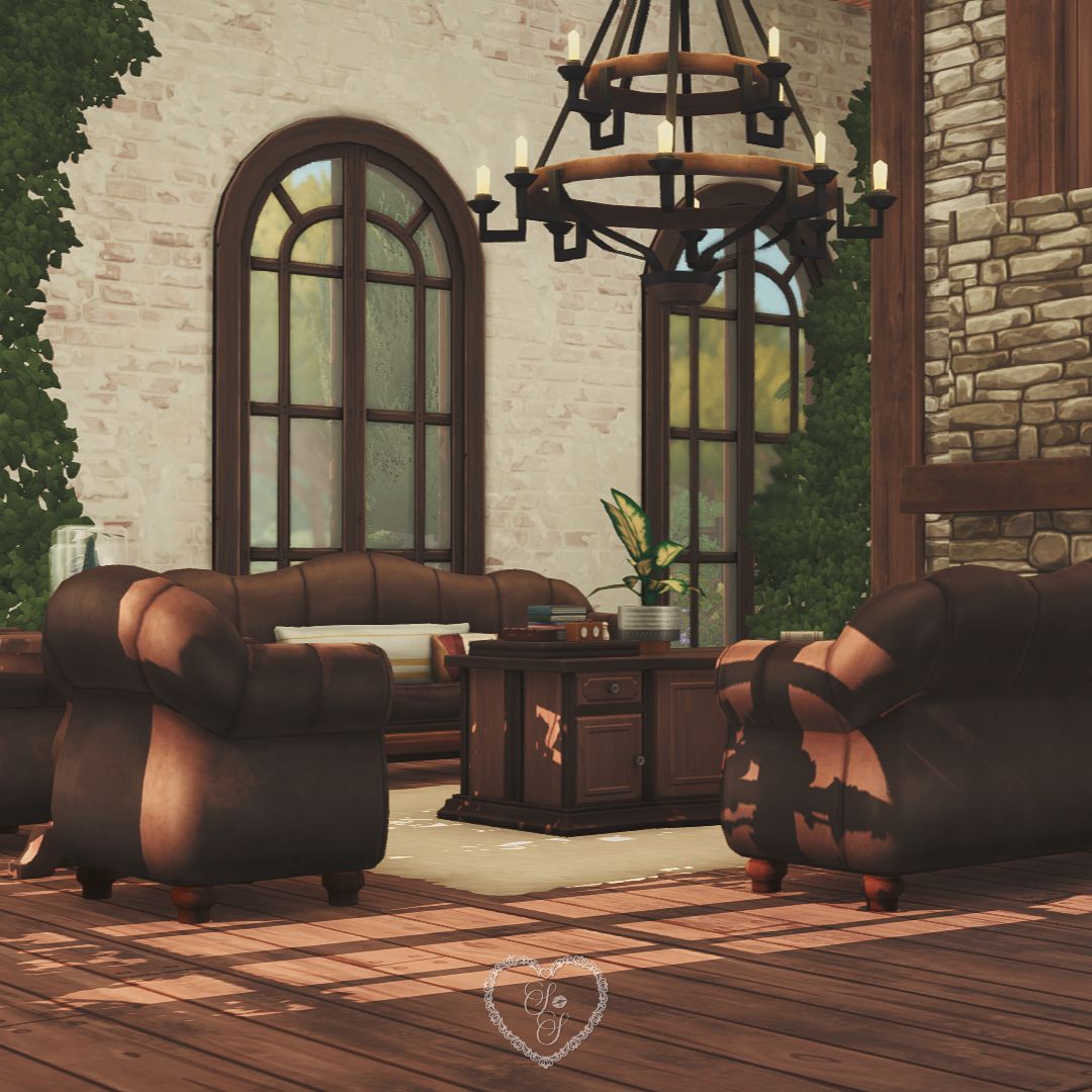Cozy living room with brown leather armchairs, arched windows, a stone fireplace, and leafy green ivy accents.