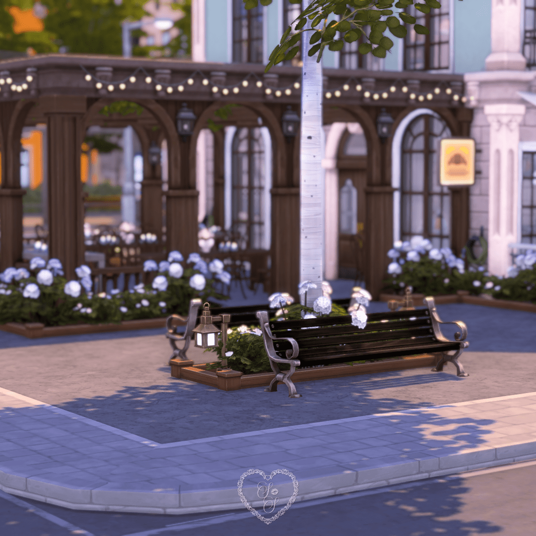 A black park bench with vintage lanterns and blooming hydrangeas under romantic string lights outside the café.