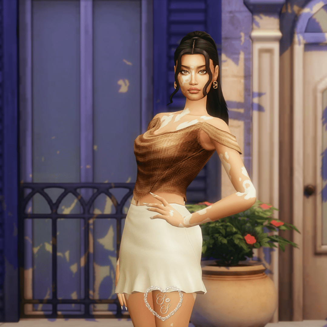 A close-up of Fernanda showing the draped Betsy Top in a neutral palette, paired with gold accessories.