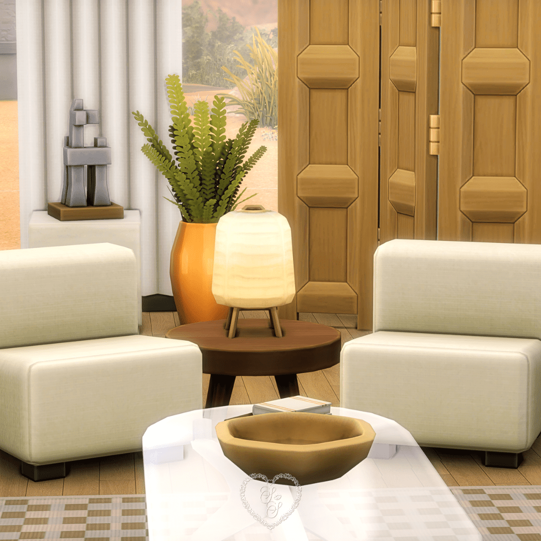 A cozy seating area from the Refined Living Room build featuring two plush chairs, a soft-glow lamp on a round wood table, and a modern sculptural piece by the window.