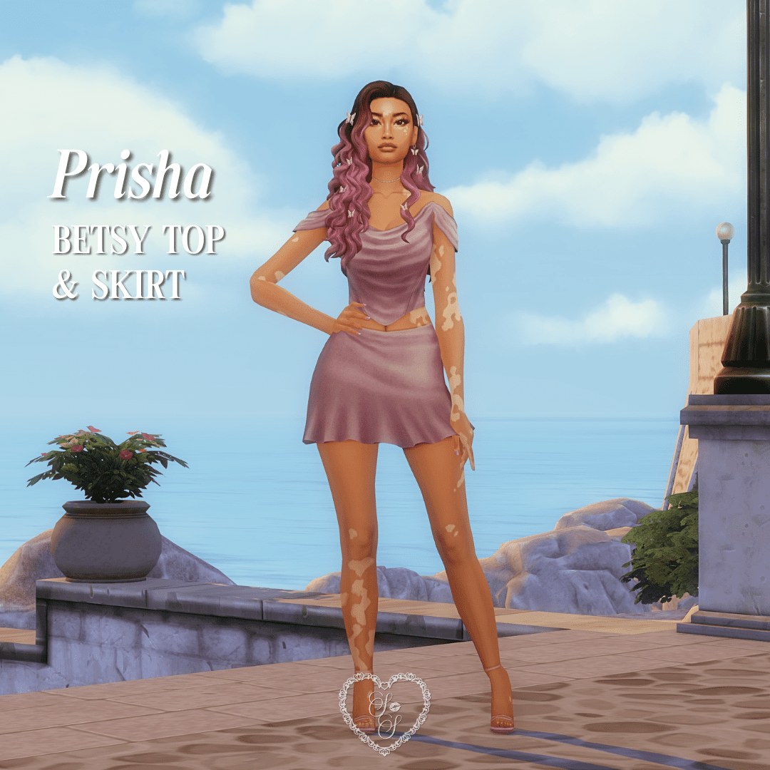 Prisha stands by the ocean in the Betsy Top and Skirt in soft mauve, styled with butterflies in her hair.