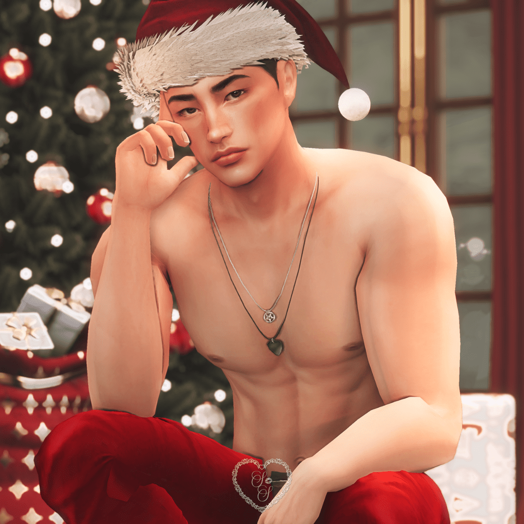 A moody seated shot of Taeyang in a Santa hat, posed in front of a glowing tree and holiday decor, hand resting near his face.