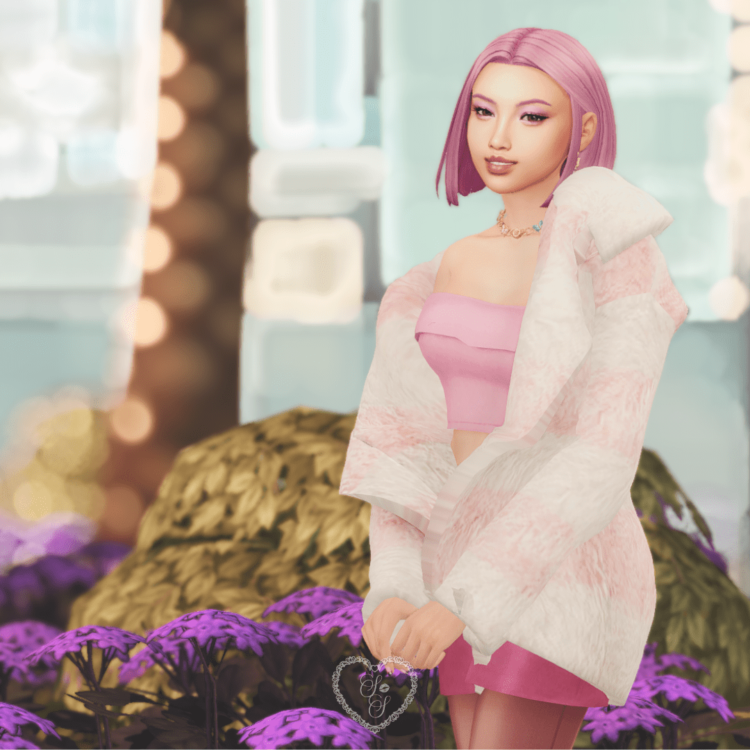Anaya Mori smiling sweetly while standing in front of purple flowers, wearing a pink fur jacket and strapless crop top.
