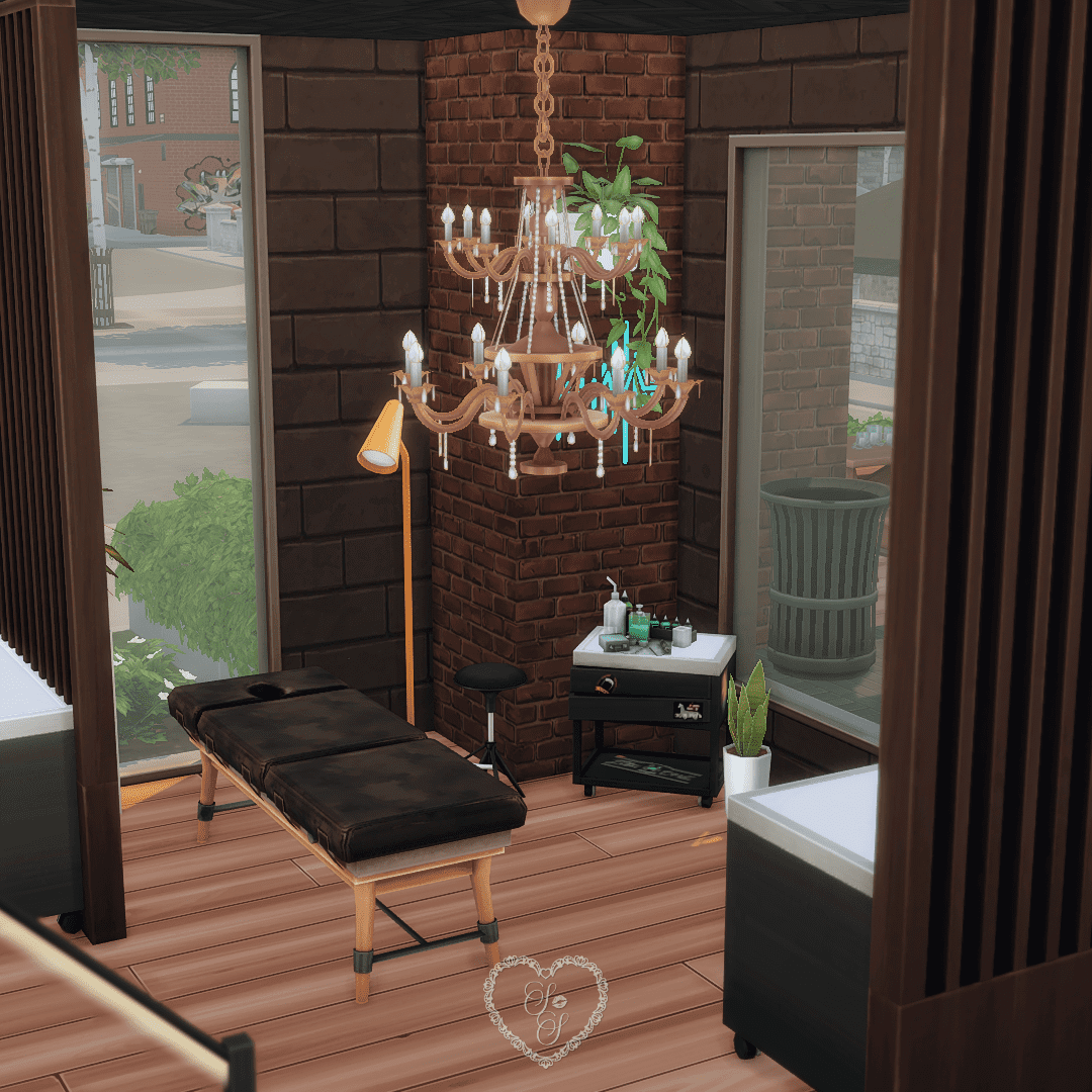 One of the four tattoo booths in this Sims 4 Tattoo Shop build, featuring a fold-out table, pendant chandelier, wall plant, and ink supply station.